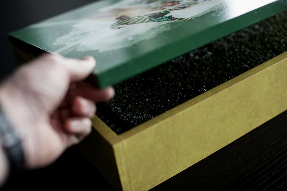 A hand lifts the book out of the box